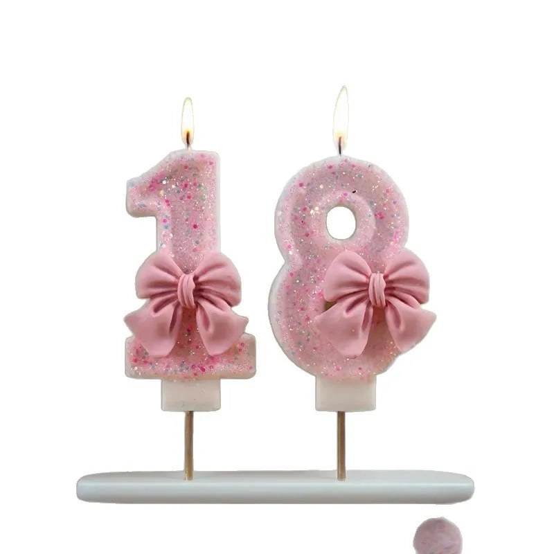 Two pink glitter number candles, one '1' and one '8', displayed on a white stand.