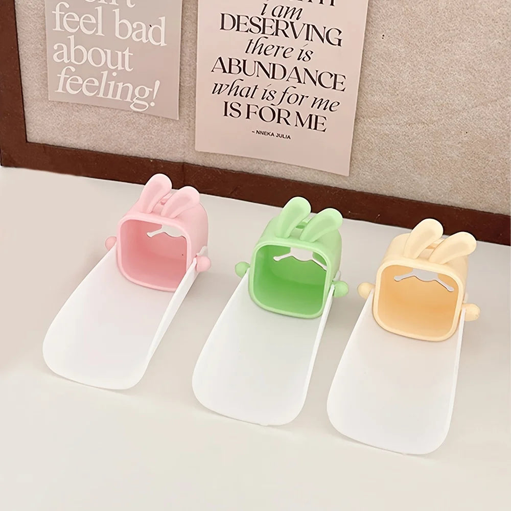 Three anti-splash faucet extenders in pink, green, and yellow with cute rabbit designs displayed on a white surface.
