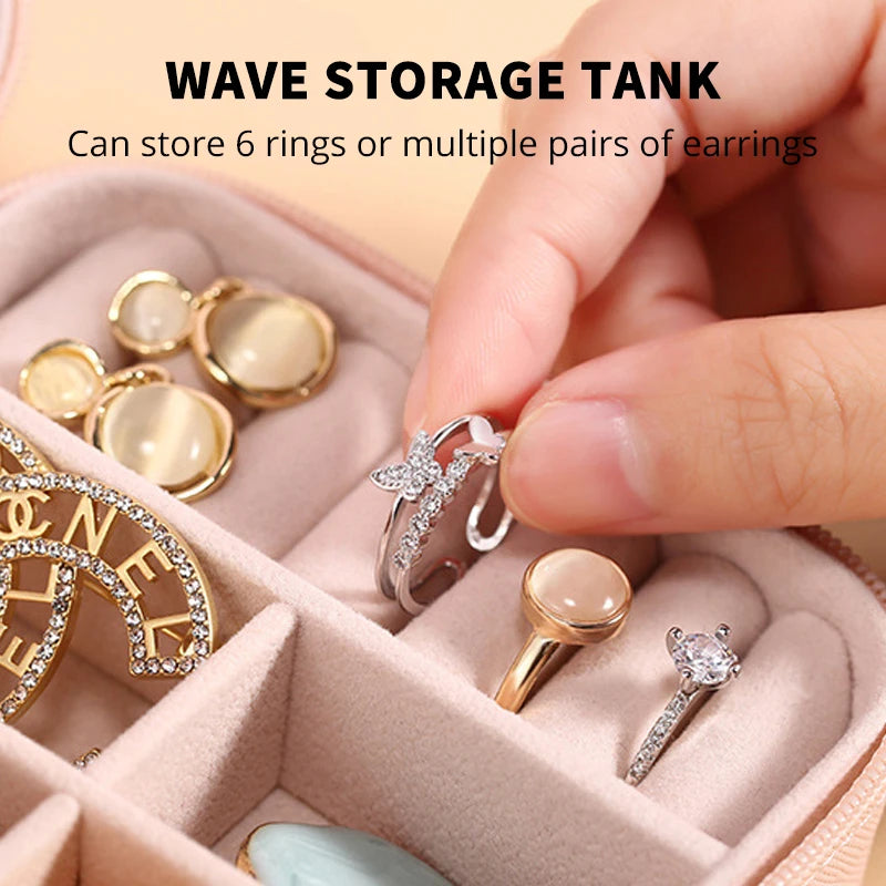 A hand is placing silver rings and earrings into a pink wave storage tank for jewelry organization.