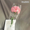 Un bouquet de cœurs roses faits main en coton, avec le mot LOVE écrit sur la tige.
