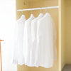 White shirts hanging on a silver rod inside a light yellow closet or cabinet.
