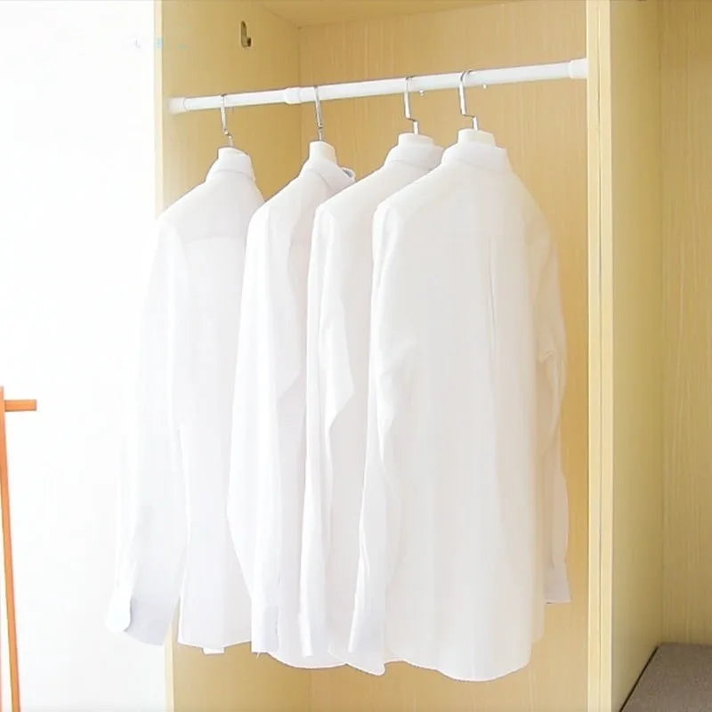 White shirts hanging on a silver rod inside a light yellow closet or cabinet.