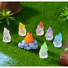 A collection of luminous resin mini fairy gnomes in various colors resting on bright green grass.