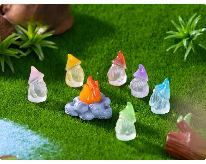 A collection of luminous resin mini fairy gnomes in various colors resting on bright green grass.