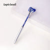 A silver pen with a blue lapis lazuli crystal top and body resting on a white surface.