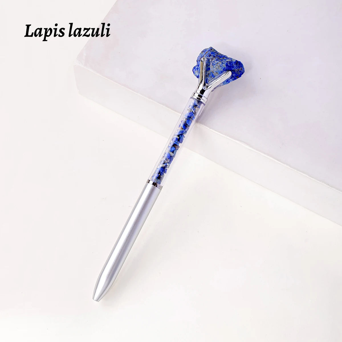 A silver pen with a blue lapis lazuli crystal top and body resting on a white surface.