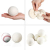 Hands are shown using reusable white wool dryer balls for clothes drying.