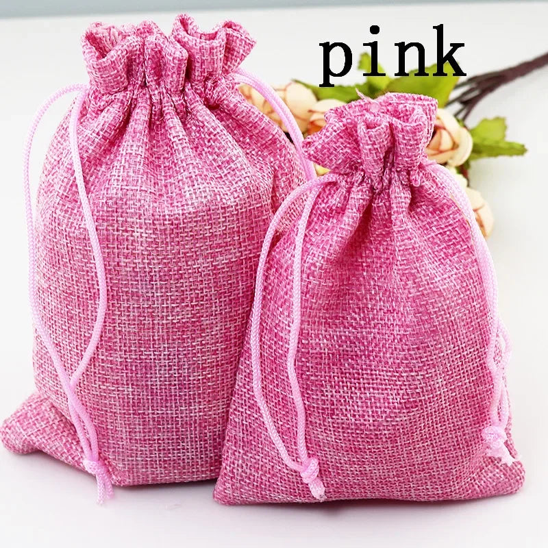 Zwei rosa handgefertigte Geschenkbeutel aus Jute und Leinen auf einer weißen Oberfläche.