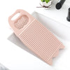 A pink durable plastic washing board with ridges and a handle is shown on a white surface.