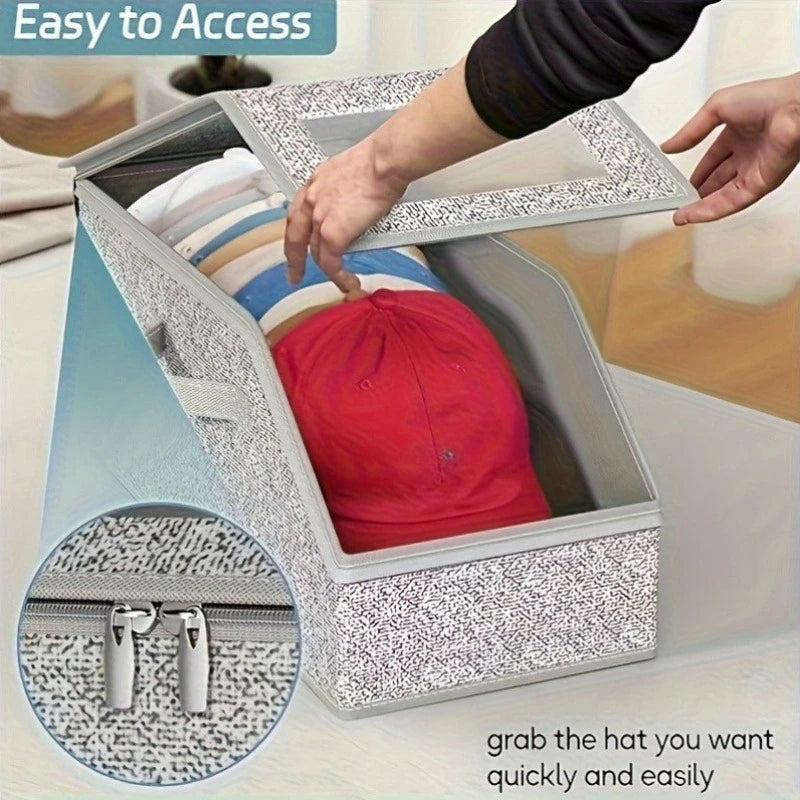 A gray fabric hat storage box with a zipper is shown open, revealing a red hat inside.