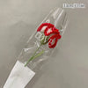 Bouquet de cœurs de cornes de coton fait main avec des pétales rouges et une tige verte dans une gaine en plastique transpare