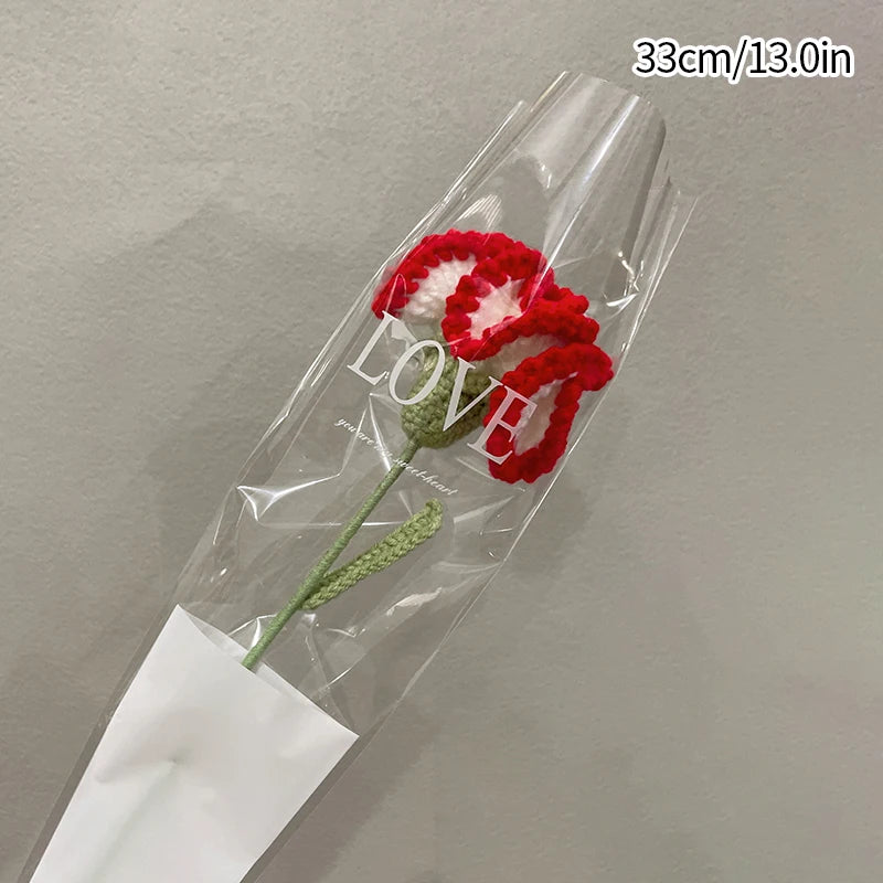Bouquet de cœurs de cornes de coton fait main avec des pétales rouges et une tige verte dans une gaine en plastique transpare