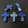 Four blue agate and jasper cross pendant charms arranged on a dark surface.