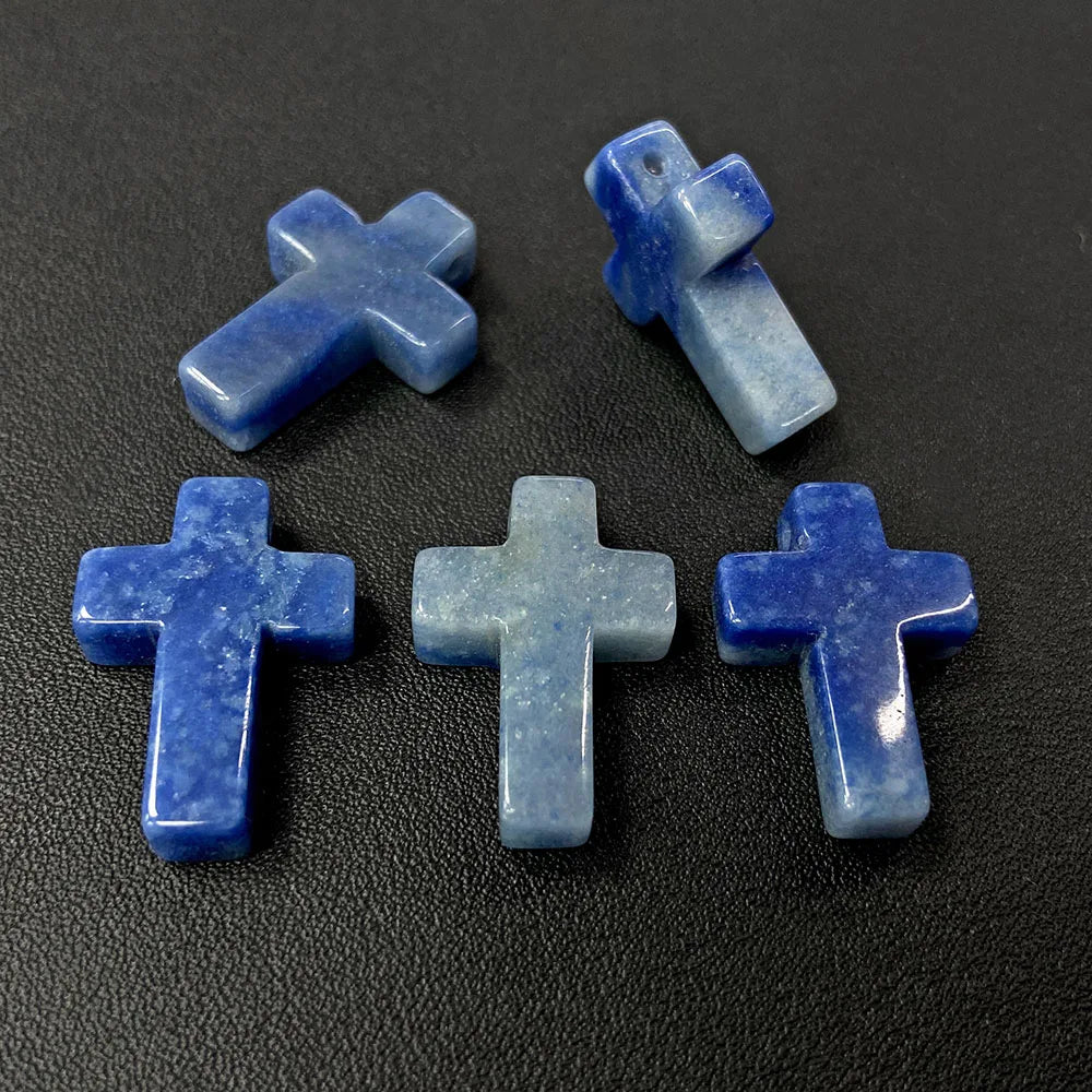 Four blue agate and jasper cross pendant charms arranged on a dark surface.