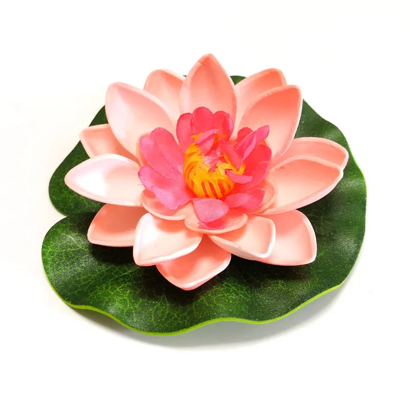 A pink artificial lotus flower with orange center resting on a green leaf.