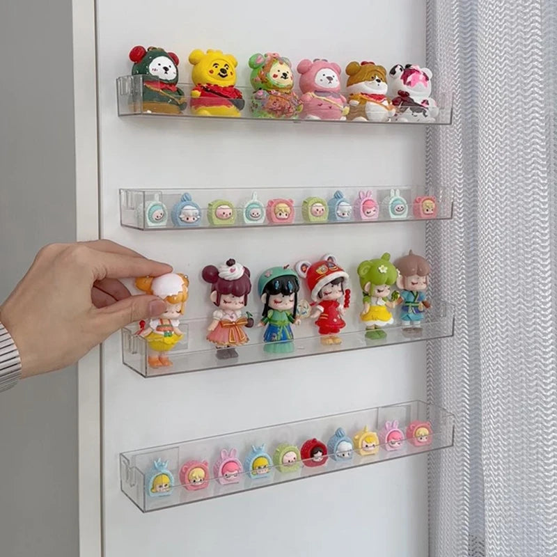 A hand places small collectible figures into a wall mounted acrylic display shelf for collectors.