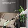 A handheld electric cleaning brush with a light green handle is shown next to a potted plant on a brown leather chair.