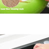 A hand is using a sand fiber cleaning cloth to wipe a striped sponge in a green bowl.
