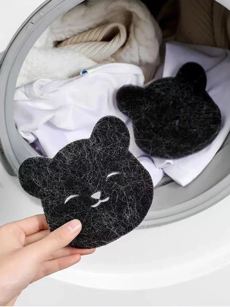 A hand holds a black, fuzzy pet hair remover sponge against a white background.