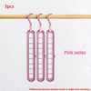 Three pink plastic foldable hangers hanging from a wooden rod.