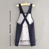 A navy and white waterproof sleeveless kitchen apron with an X-shaped design hanging on a wooden hanger.