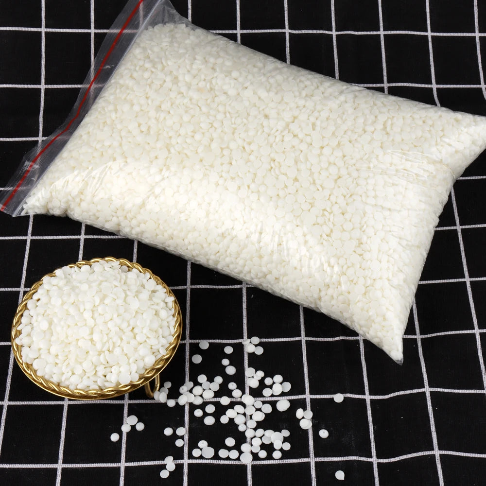 Bolsa blanca de material para hacer velas de cera de soja natural con gránulos sueltos sobre una superficie de rejilla negra.