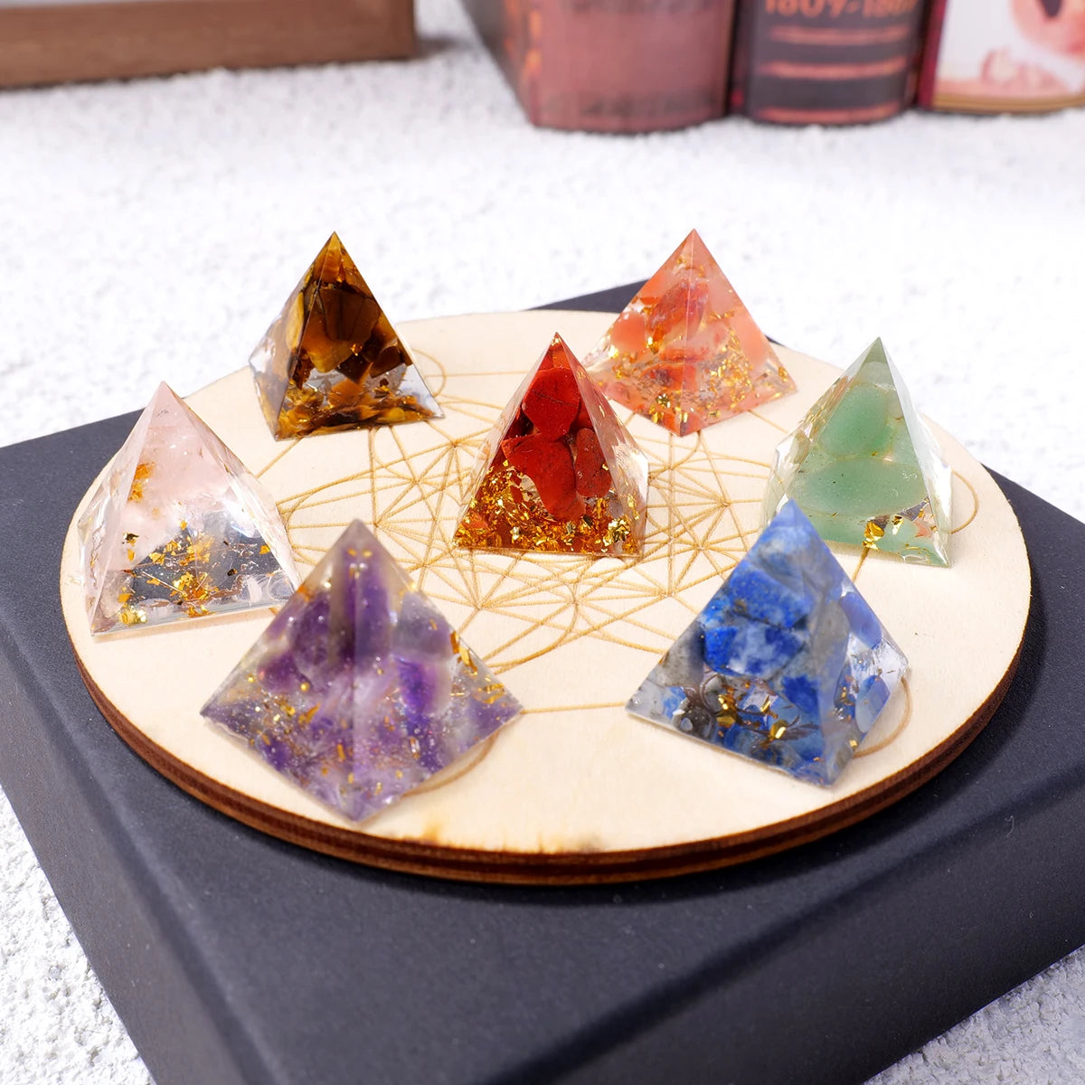A set of natural stone pyramid crystals in various colors like amber, red, green, and blue arranged on a wooden surface.