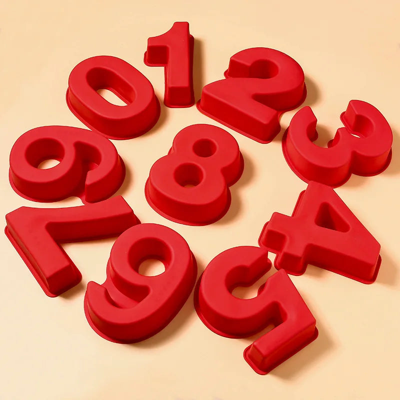 Red silicone number cake molds shaped like the digits 1, 2, 3, 4, 5, 6, 7, 8, and 9 scattered on a light background.