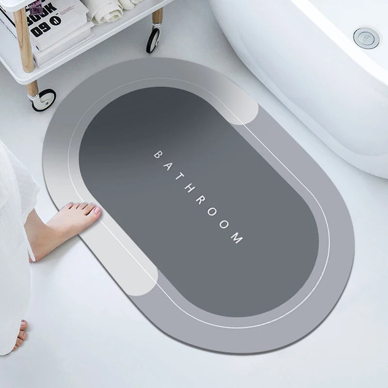 A gray bath mat with the word BATHROOM embossed on it is placed next to a white toilet bowl.