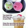A close-up of clear reusable disposable coffee cups with pink and green lids, emphasizing a flap cap feature.