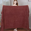A woman is displaying a large, deep red microfiber bath towel draped over her shoulders.