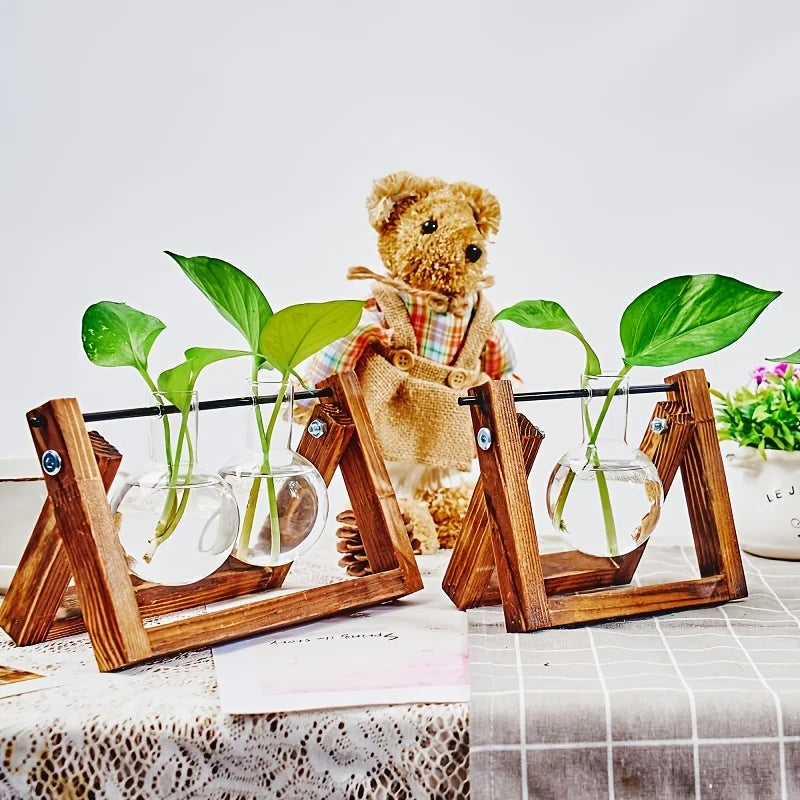 Estación de propagación de plantas de madera con frascos de vidrio, plántulas verdes y un oso de peluche.