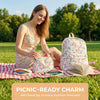 A smiling woman lies on the grass with a floral print backpack, handbag, and pencil case set.