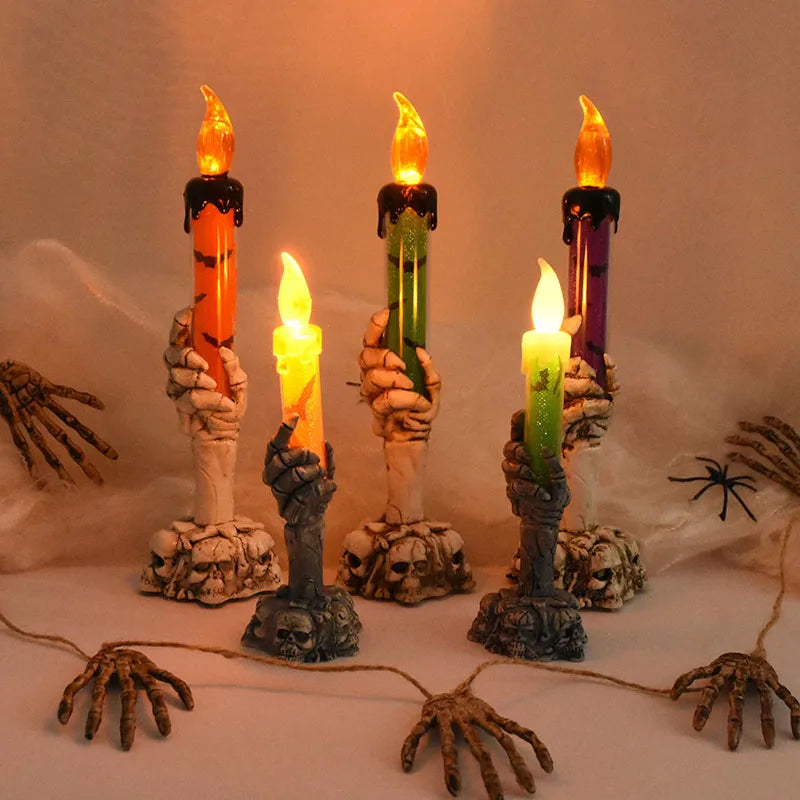 A display of skeleton hand shaped LED candles in orange, green, and purple hues.