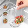 Reusable mesh strainer bags filled with colorful vegetable scraps being held over a kitchen drain.