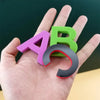Eine Hand hält ein magnetisches Alphabet-Lernset mit den Buchstaben A und B in Lila und Grün.