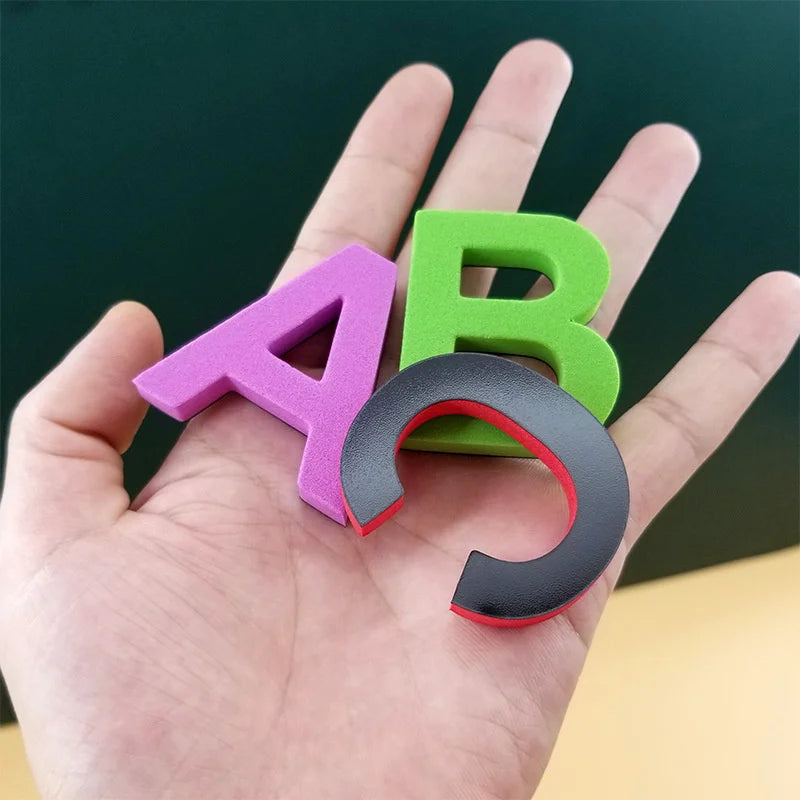 Eine Hand hält ein magnetisches Alphabet-Lernset mit den Buchstaben A und B in Lila und Grün.