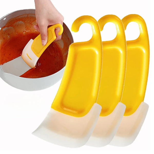 A set of yellow silicone kitchen cleaning spatulas being used in a bowl.