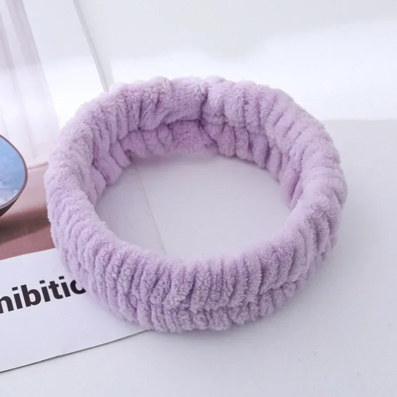 A purple microfiber wrist sweatband set for face washing and skincare is shown on a white surface.