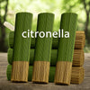 Green citronella oil sticks standing upright in a row on a wooden surface.