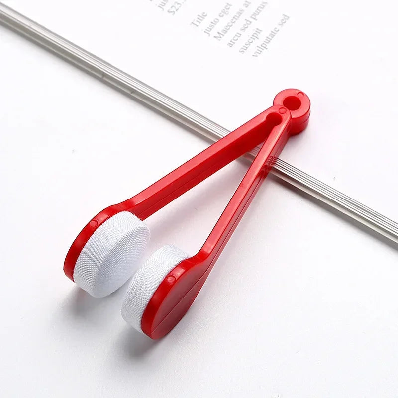 A red and white two-sided microfiber cleaning brush set for eyeglasses resting on a white surface.