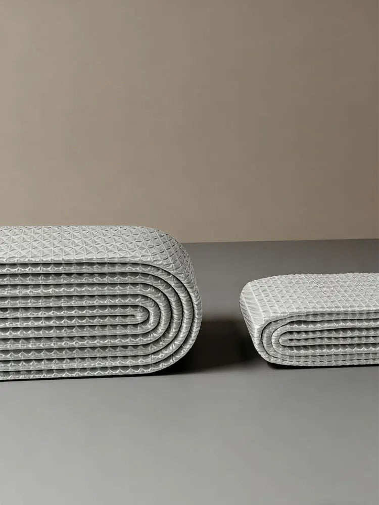 A stack of white no-drill magnetic shower curtains with a waffle texture on a gray surface.