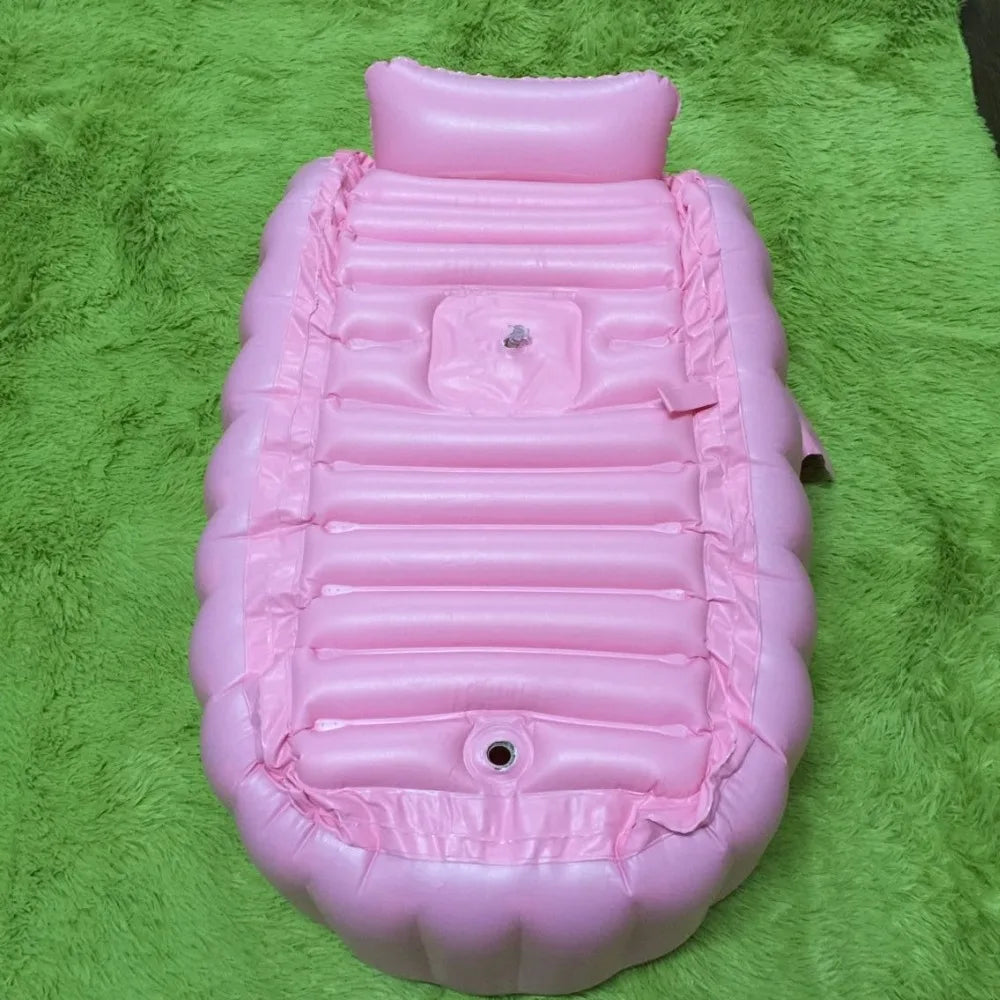 A pink inflatable bath tub for kids resting on a green fuzzy surface.