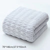 A stack of light gray textured bath towels folded neatly on a white surface.