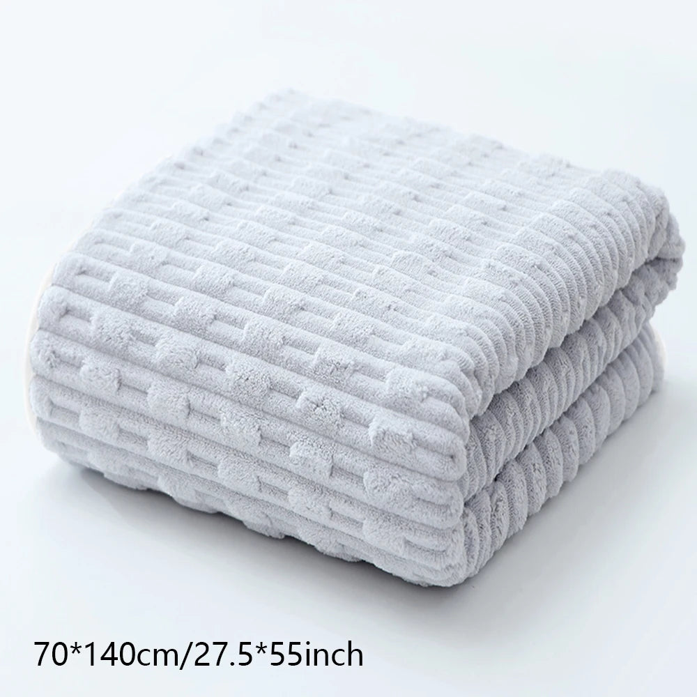 A stack of light gray textured bath towels folded neatly on a white surface.