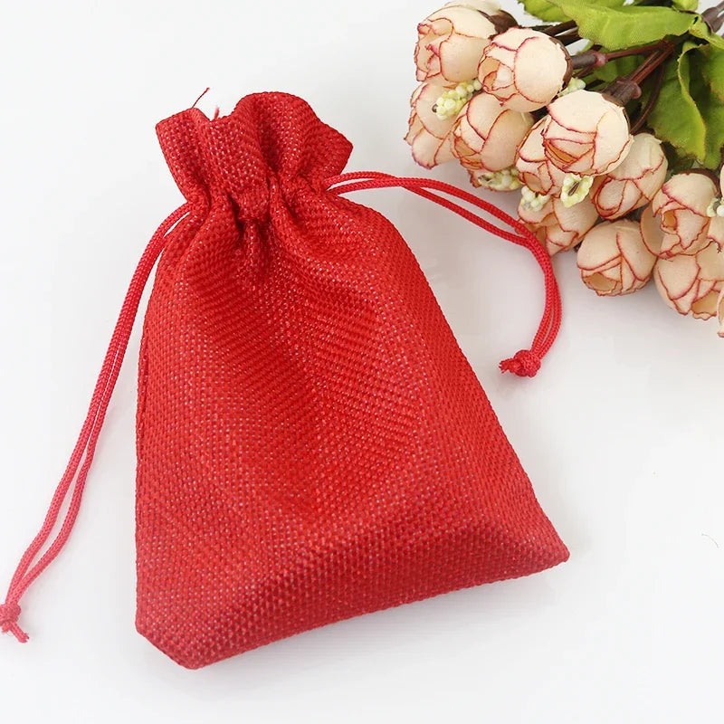 Helles rotes Jute- und Leinen-Geschenkbeutel mit einem grünen Pflanzenzweig daneben