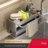 A stainless steel countertop drain basket with a rod holding sponges and dish tools.