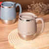 A beige insulated stainless steel travel mug with a silver lid resting on a wooden surface.