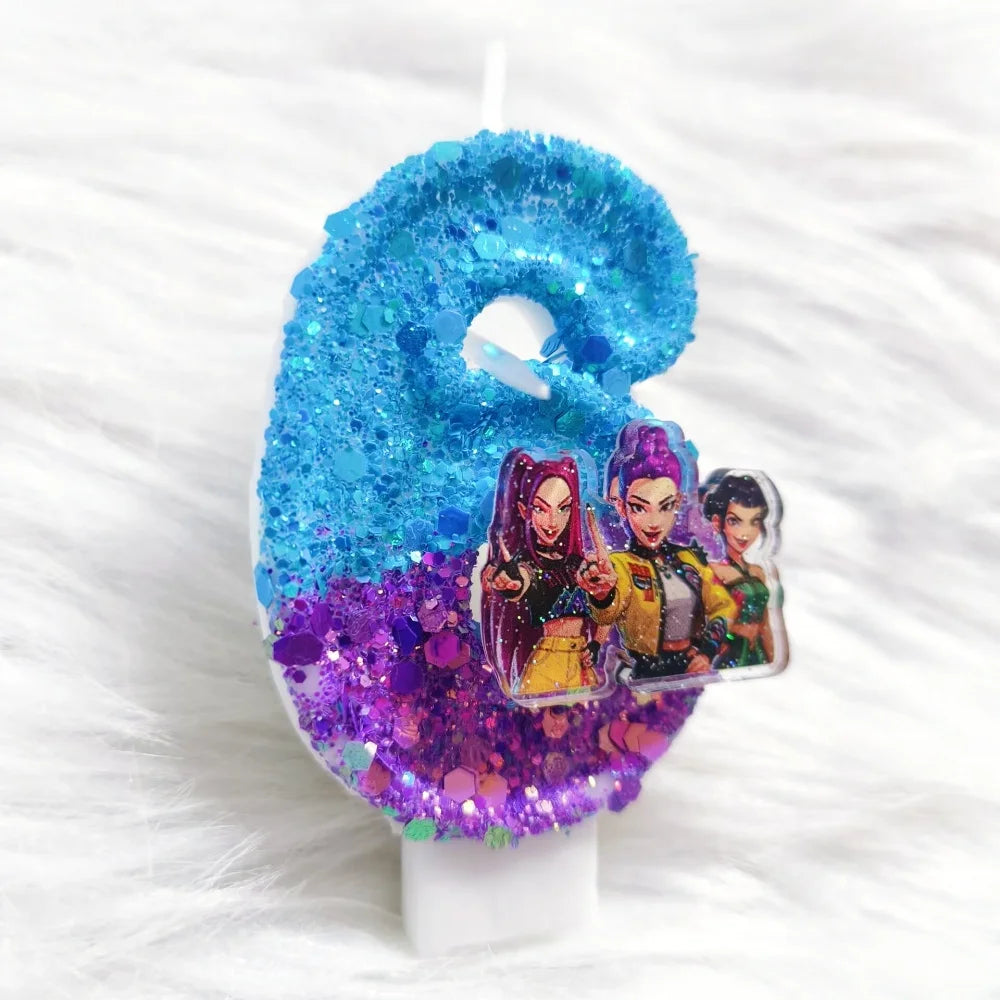A birthday candle decorated with blue glitter and purple glitter featuring small character charms.