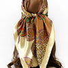 A square paisley print scarf in gold and brown tones tied around a dark hair
